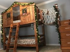 a wooden bunk bed with christmas lights on the top and bottom, next to a dresser