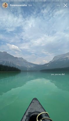 the view from a kayak looking out at mountains and water with clouds in the sky