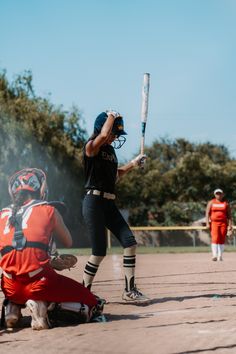 a baseball player holding a bat on top of a field in front of other players