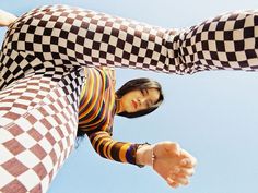 a woman in checkered leggings reaching up into the air with her hand