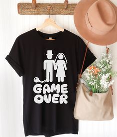 a t - shirt with the words game over printed on it next to a hat and purse