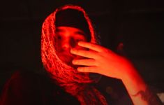 a woman wearing a red scarf is holding her hand up to her face in the dark