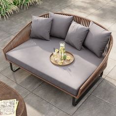 a wicker couch with grey cushions and drinks on it