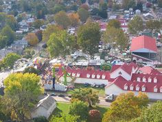 an aerial view of a carnival park with lots of trees and buildings in the background