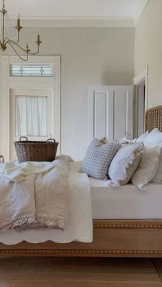 a bed with white linens and pillows in a bedroom next to a chandelier