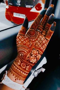 a woman's hand with henna on it in front of a car window