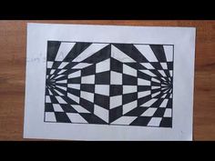 a piece of paper with black and white designs on it sitting on a wooden table