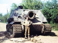 a man standing in front of an old tank