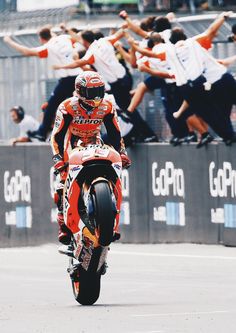 a man riding on the back of a red motorcycle down a race track with other people behind him