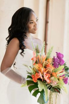 a woman holding a bouquet of flowers in her hand and looking off into the distance