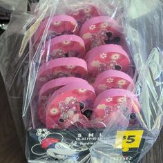 a plastic bag filled with pink frisbees on top of a wooden table