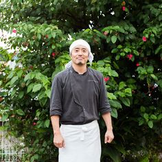 a man standing in front of a bush wearing an apron and chef's hat