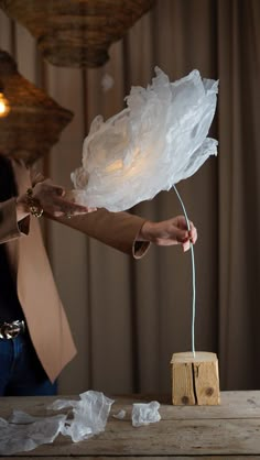 a woman is holding something in her hand while standing next to a table with tissue on it