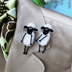 two small black and white sheep are on the lapel or back of a jacket