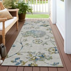 a white rug with blue and yellow flowers on the floor next to a wooden bench