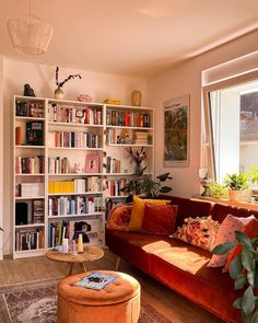 a living room filled with lots of furniture and bookshelves next to a window