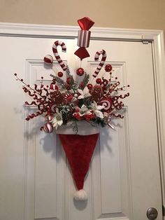 a red and white christmas decoration hanging on a door with candy canes in it