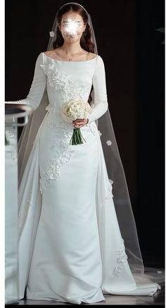 a woman in a white wedding dress holding a bouquet and wearing a bridal veil