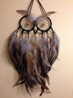 a dream catcher hanging on the wall with feathers and beads around it's eyes