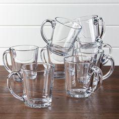 a set of six glass mugs sitting on top of a wooden table