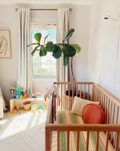 a baby's room with a crib in the corner and a potted plant on the window sill