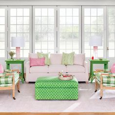 a living room filled with lots of furniture next to two lamps and large windows in the background