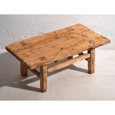 an old wooden table sitting in front of a white brick wall with no one on it