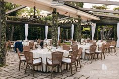 an outdoor dining area with tables and chairs set up for a formal function in the garden