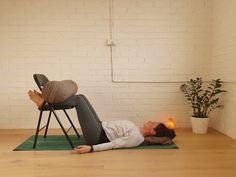 a woman laying on top of a green mat in front of a white brick wall