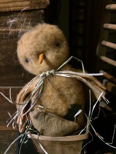 a teddy bear sitting in a basket with some string wrapped around it's neck