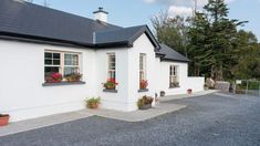 a white house with potted plants on the windows and gravel driveway in front of it