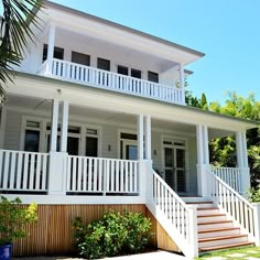 a white two story house with balconies on the front porch and stairs leading up to the second floor