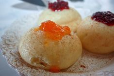 three desserts on a plate with powdered sugar and jelly in the top one