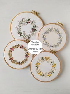 four embroidery hoops with floral designs on them and the words wreaths 4 seasons