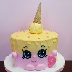 a cake with an ice cream cone on top of it, decorated in pink and yellow icing