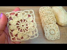 two crochet doilies are being held by a woman's hand on a wooden surface