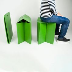 a woman sitting on top of a green box next to two small pieces of paper