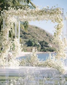 an outdoor wedding setup with white flowers and chairs