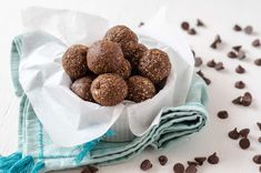 a bowl filled with chocolate energy bites on top of a blue towel next to some chocolate chips