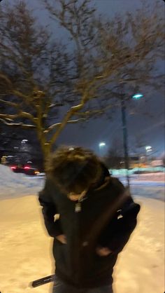 a man riding skis down a snow covered slope next to a tree at night