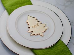 a white plate topped with a gold christmas tree brooch sitting on top of a green napkin