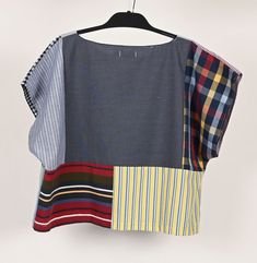 a shirt that has different colors and patterns on the front, hanging from a hanger