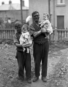 an old black and white photo of three people holding two small children in their arms