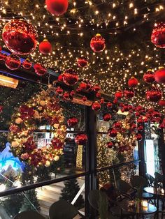 christmas decorations and lights hang from the ceiling in an indoor restaurant, decorated with red ornaments