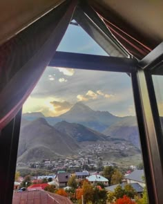 the view from inside a window looking out at mountains and houses in the valley below