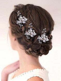 a woman wearing a wedding hair comb with flowers on it's side and pearls in her hair