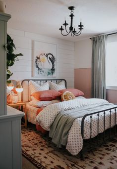 a bed room with a neatly made bed and a chandelier hanging from the ceiling