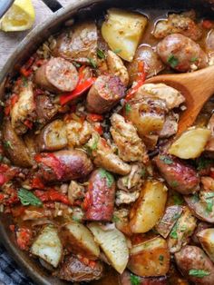 a skillet filled with potatoes, meat and sauce on top of a towel next to a wooden spoon