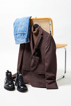 a pair of black shoes sitting on top of a chair next to a brown jacket