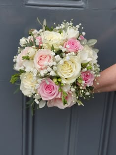 a bridal bouquet with pink and white flowers in front of a blue door,